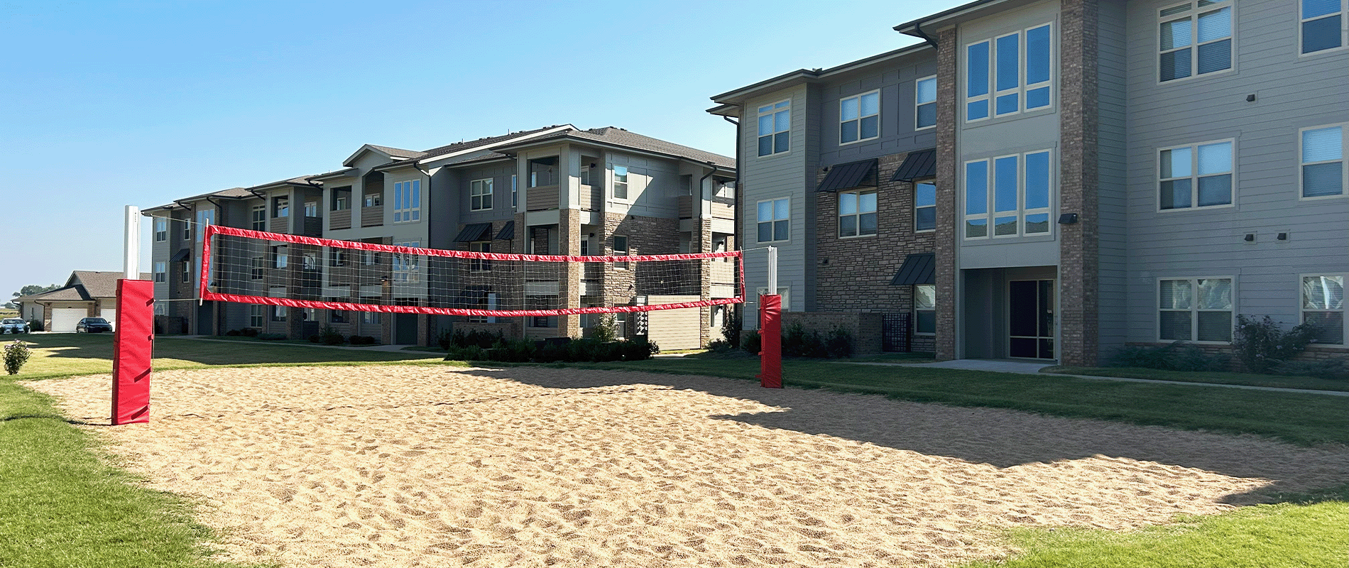 a sand volleyball court in front of an apartment complex
